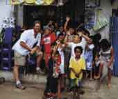 Photo shows Rod Donald with a group of Pacific Island children. 