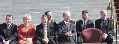 Photo shows a group of Cabinet Ministers seated in front of  Parliament buildings. 