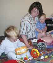 Photo shows mother playing with two small children.