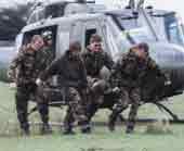 Photo shows military personel carrying a stretchered patient from a helicopter. 