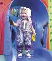 Photo shows small girl at the top of a slide. 
