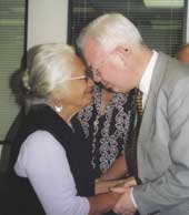 Photo of Merimeri Penfold greeting a middle aged man with a hongi. 