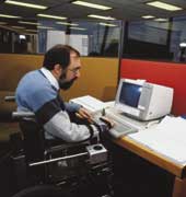Photo of male worker in a wheelchair at his office work station. 