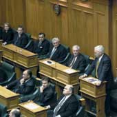 Photo shows Richard Prebble standing to speak to seated parliamentarians in the Debating Chamber. 