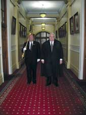 Photo of Jonathan Hunt, The Speaker, with the mace bearer carrying the mace. 