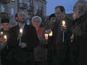 Photo shows people standing holding candles at night time peace rally. 