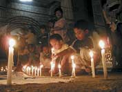Photo shows people placing lighted candles on the ground during a peace rally. 